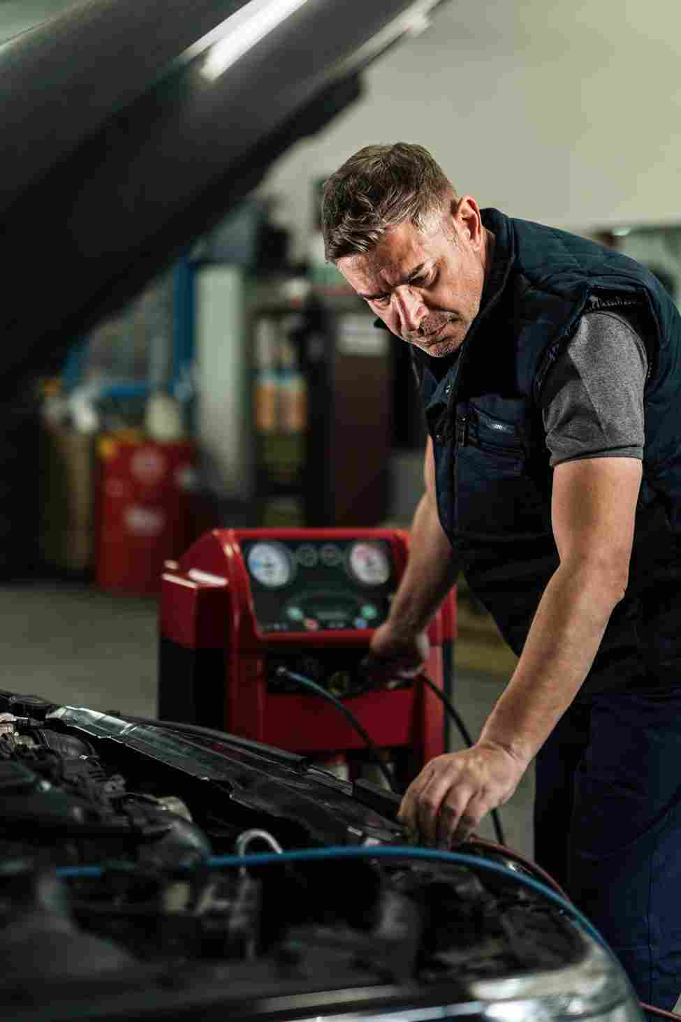 mid adult mechanic using diagnostic tool while repairing air conditioning system car auto repair shop_11zon